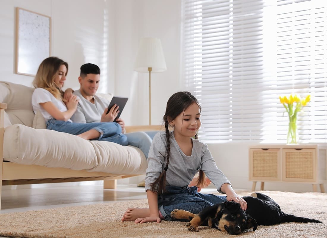 Service Center - Little Girl Playing With Puppy While Parents Sitting on Sofa in Living Room